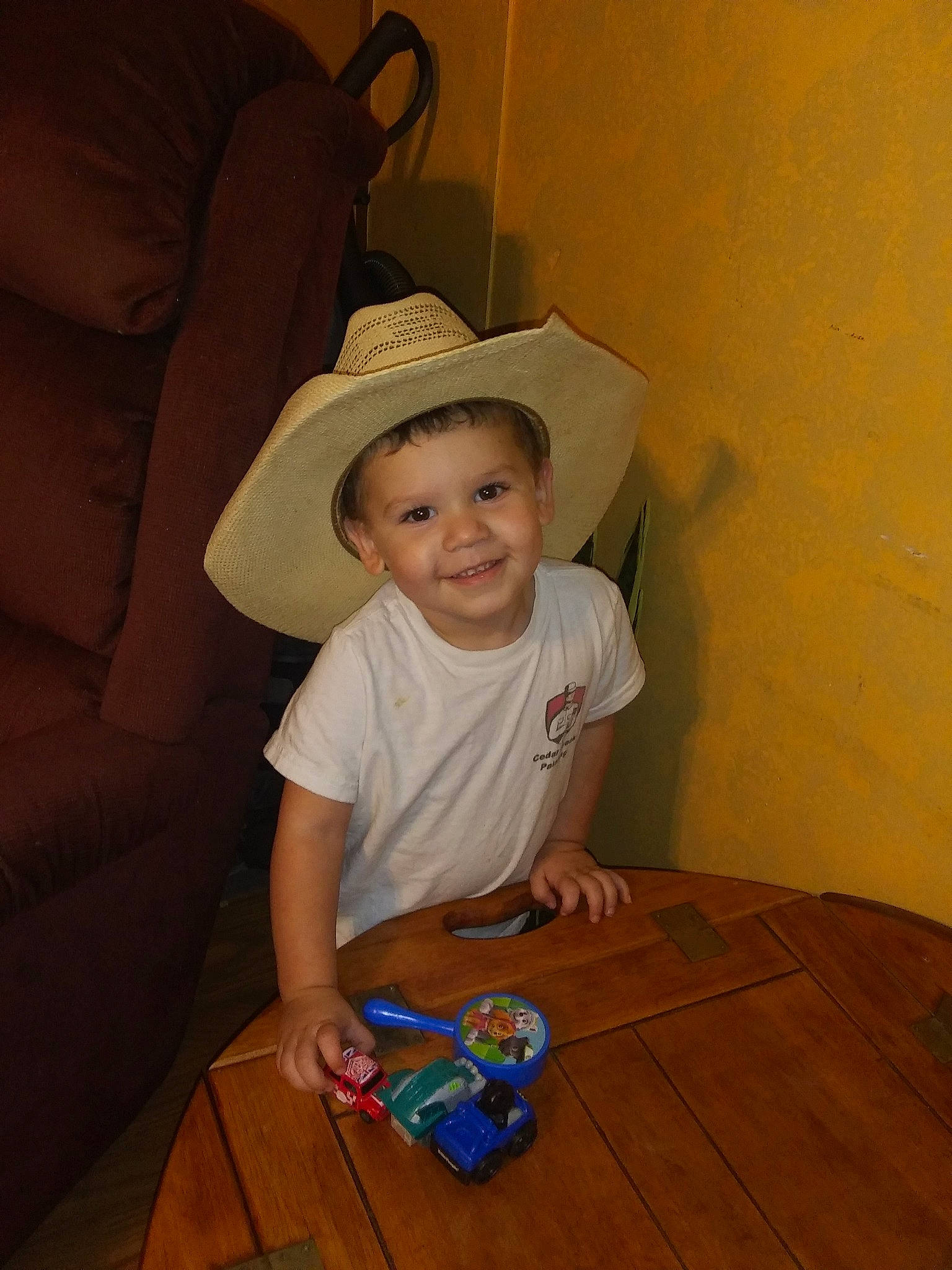 Riot is registered to the contest to win money with this photo: child, floor, fun, hat, headgear, joy, lighting_accessory, person, play, sitting, skin, smile, toddler, vacation, wood