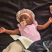 Chloe is registered to the contest to win money with this photo: baby, sleeping, pacifier, pink_clothing, blanket, bonnet, infant, arms_outstretched, cozy, rest, cute, newborn, soft_fabric, indoor, peaceful, child, face, headwear, relaxation, comfort