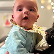 Manoa a rejoint le concours — aidez-le/la à gagner de superbes lots ! baby, bib, blurred_background, bokeh, child, clothing, cozy, cute, expression, face, hand, holding, indoors, infant, person, portrait, skin, soft_texture, warm_lighting, young