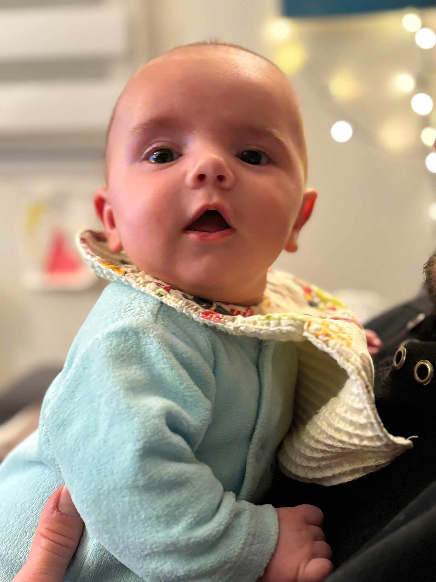 Manoa a rejoint le concours — aidez-le/la à gagner de superbes lots ! baby, bib, blurred_background, bokeh, child, clothing, cozy, cute, expression, face, hand, holding, indoors, infant, person, portrait, skin, soft_texture, warm_lighting, young