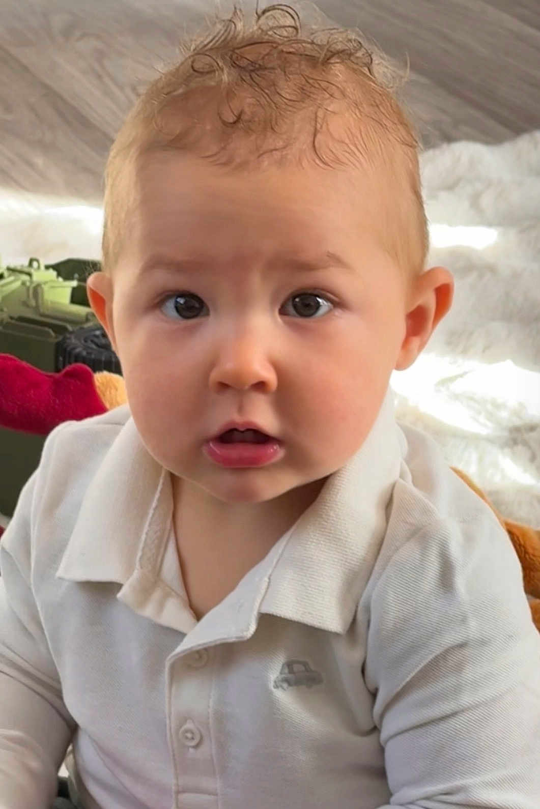 émilio a rejoint le concours — aidez-le/la à gagner de superbes lots ! baby, child, curly_hair, white_shirt, portrait, indoor, cute, face, eyes, expression, infant, soft_lighting, toy, curious, young_child, person, sitting, closeup, head_and_shoulders, casual_clothing