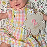 baby, checked_outfit, child, close_up, colorful_clothing, diaper, dress, face, floral_blanket, flower_shape, happy, indoor, infant, lying_down, milestone_sign, photography, portrait, smiling, socks, two_months