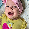 Chloe is registered to the contest to win money with this photo: baby, child, infant, smiling, happy, portrait, face, headband, pink, yellow, outfit, dress, pacifier, blanket, bed, indoor, close_up, sitting, fashion, cute