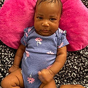 Azaliah joined the competition — help win amazing prizes! baby, infant, child, onesie, blue_clothing, pink_pillow, hand, skin, face, expression, black_background, fabric, patterned_blanket, cute, portrait, indoors, sitting, young_child, human, closeup
