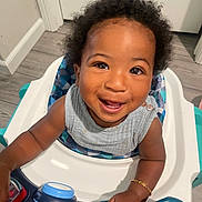 Suede is registered to the contest to win money with this photo: toddler, child, smiling, high_chair, toy, indoor, happy, face, curly_hair, arm, clothing, floor, door, bracelet, baby, play, seat, person, expression, closeup