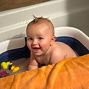Kaysen joined the competition — help win amazing prizes! baby, bathtub, bath, water, rubber_duck, toy, orange_towel, child, smiling, wet_hair, skin, indoor, happy, cute, infant, playful, splashing, fun, tub, portrait