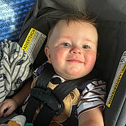 Kaysen is registered to the contest to win money with this photo: baby, child, car_seat, smile, blue_eyes, striped_shirt, blanket, toy, seatbelt, infant, close_up, indoors, cute, happy, young_child, soft_lighting, face, person, safety, comfort