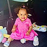 toddler, child, smile, pink_dress, baby_bottle, car_interior, seatbelt, soft_toys, happy, sitting, cute, hair_bun, earrings, footwear, playful, portrait, indoors, car_seat, baby, colorful