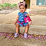toddler, child, denim_dress, pink_bow, pink_handbag, purple_sandals, concrete_ledge, flower_petals, fallen_leaves, outdoor, curious_expression, sidewalk, brick_wall, window, greenery, summer, cute, fashion, portrait, casual