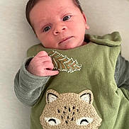 Noah a rejoint le concours — aidez-le/la à gagner de superbes lots ! baby, infant, child, green_clothing, embroidered_animal, cute, lying_down, soft_surface, alert, hand, face, portrait, young_child, text_on_clothing, cozy, indoors, expression, skin, eyes, head