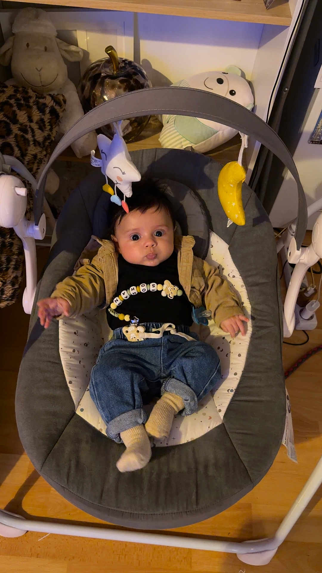 Sohan participe au concours pour gagner de l'argent avec cette photo : baby, infant, baby_rocker, plush_toy, banana_toy, denim_pants, black_shirt, baby_accessories, indoor, wooden_floor, smiling_toy, stuffed_animal, baby_clothing, baby_boy, child, face, cute, relaxing, home, furniture