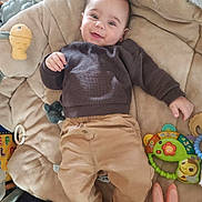 Lyo participe au concours pour gagner de l'argent avec cette photo : baby, smiling, toy, cushion, clothing, infant, child, playtime, cute, happy, indoors, soft_toy, colorful, comfortable, face, person, sitting, blanket, small_child, cozy