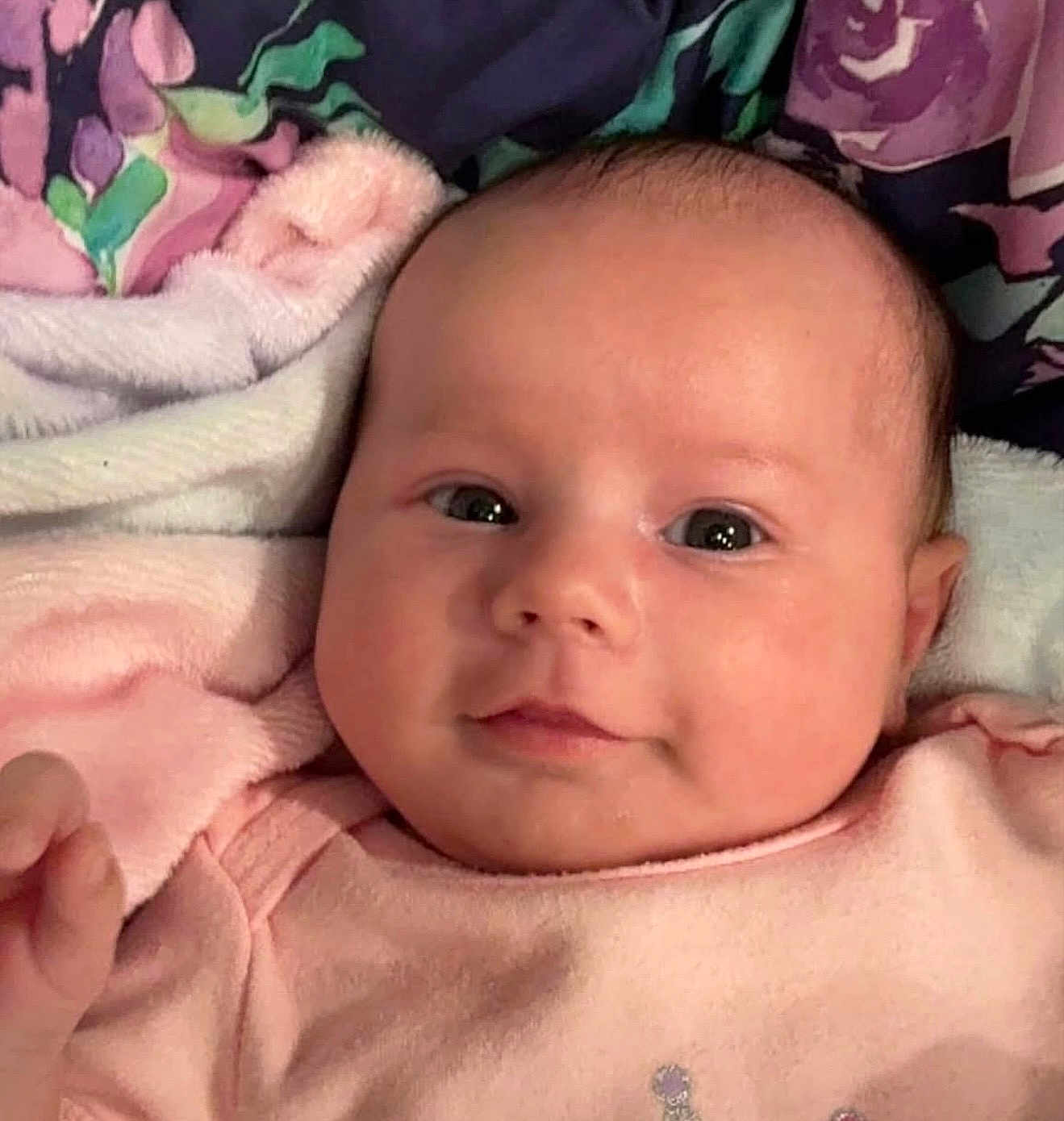Miley is registered to the contest to win money with this photo: baby, infant, face, eyes, blanket, pink_clothing, soft_texture, closeup, newborn, cute, child, portrait, indoors, skin, head, expression, lying_down, small_hand, warm, comfort