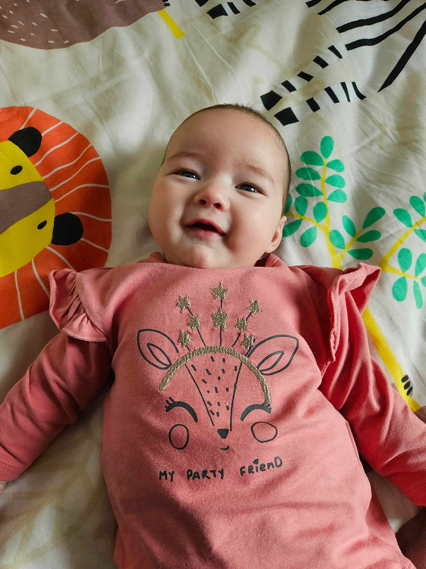 Hélya a rejoint le concours — aidez-le/la à gagner de superbes lots ! baby, infant, smiling, onesie, blanket, pillow, bedding, pattern, animal_print, cute, happy, face, eyes, cheeks, mouth, glitter, sparkles, shirt, lying_down, indoors
