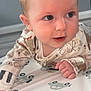 baby, child, infant, face, blue_eyes, onesie, animal_print, hand, floor, mat, pattern, car_pattern, cute, curious, indoor, portrait, young_child, skin, head, expression