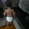 toddler, child, diaper, walking, back_view, indoor, couch, gray_furniture, wooden_floor, purple_wall, baby, person, home, living_room, soft_lighting, curly_hair, bare_back, movement, young_child, casual