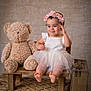 Ashley joined the competition — help win amazing prizes! baby, teddy_bear, bench, dress, flower_crown, smile, barefoot, wooden_bench, toy, child, portrait, indoor, studio, vintage_suitcase, carpet, cute, happy, childhood, soft_toys, playful
