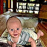 baby, infant, smiling, lying_down, blanket, wooden_floor, indoor, natural_light, dining_table, chairs, window, home, cute, person, child, patterned_blanket, happy, face, eyes, clothing