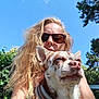 animal, blue_sky, canine, casual, closeup, collar, curly_hair, daylight, dog, grass, greenery, happy, leisure, nature, outdoor, pet, portrait, sunglasses, sunlight, woman
