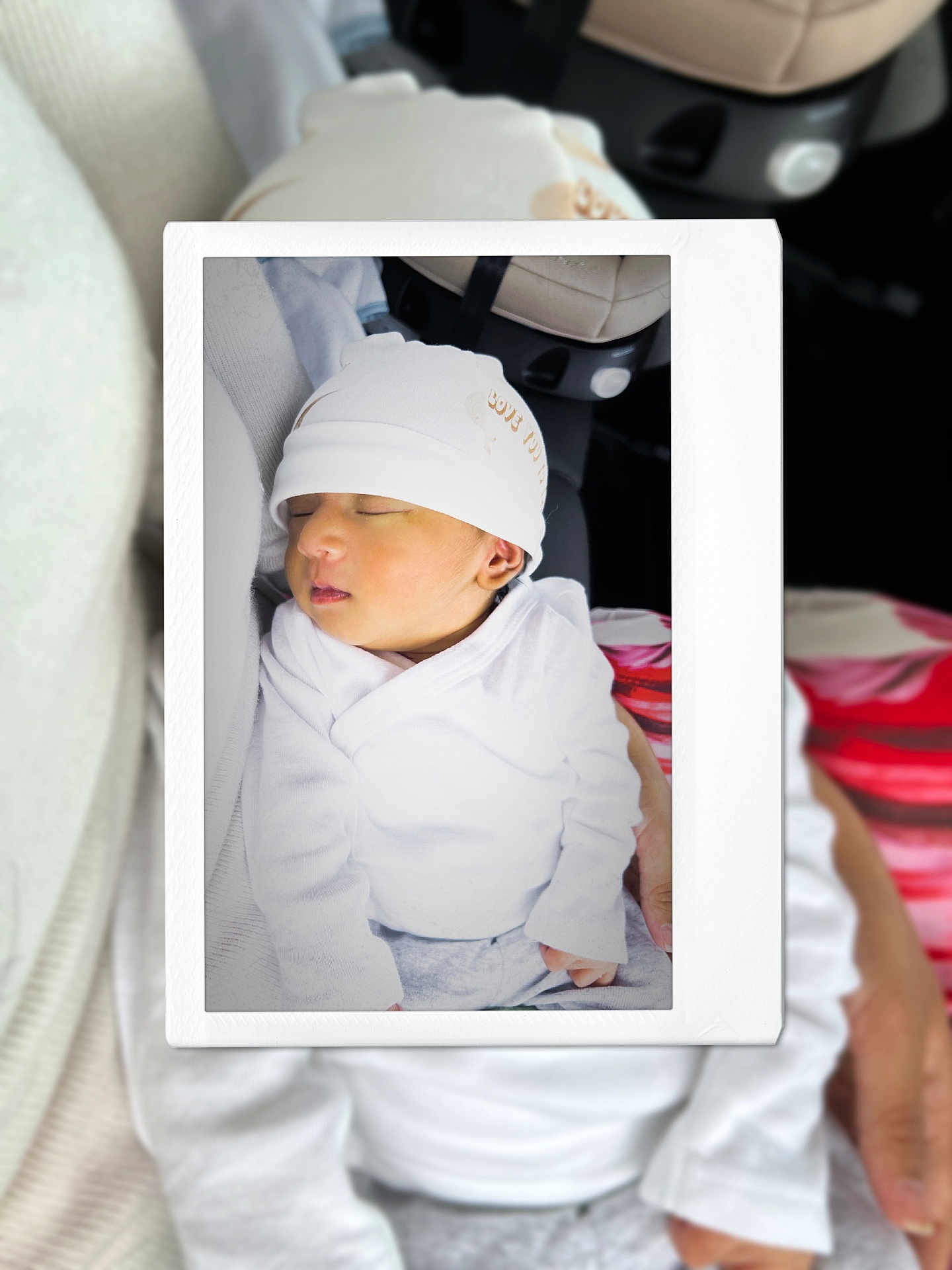 Rhythm is registered to the contest to win money with this photo: baby, sleeping, hat, white_clothing, newborn, infant, polaroid_frame, hand, soft_focus, blurred_background, person, car_seat, cute, peaceful, portrait, child, cozy, indoor, gentle_lighting, toddler