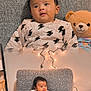 armchair, baby, child, clothing, cozy, cute, decor, furniture, happy, home, indoor, infant, plush_toy, portrait, seated, smiling, soft_lighting, string_lights, teddy_bear, toy