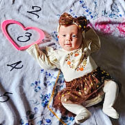 Layla is registered to the contest to win money with this photo: baby, infant, child, blanket, headband, bow, cute, smiling, laying_down, clothing, tights, skirt, pattern, numbers, heart, soft_texture, indoors, portrait, happy, festive