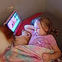 child, dog, blanket, bed, tablet, screen, sleeping, indoor, pajamas, relaxing, cozy, pink, light, face, hair, couch, resting, technology, pet, sleep