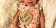 Estella joined the competition — help win amazing prizes! baby, infant, smiling, pink_outfit, bow, blanket, milestone, wooden_plaque, heart_pattern, strawberry_pattern, cute, lying_down, happy, child, person, skin, face, small_baby, indoors, soft_fabric