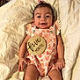 baby, infant, smiling, pink_outfit, bow, blanket, milestone, wooden_plaque, heart_pattern, strawberry_pattern, cute, lying_down, happy, child, person, skin, face, small_baby, indoors, soft_fabric
