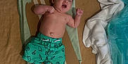 Mako joined the competition — help win amazing prizes! baby, child, swim_shorts, towel, cardboard, shark_fin, seashells, sand, fabric, blue, white, lying_down, indoors, playful, cute, infant, summer_theme, bare_chest, relaxed, decorative