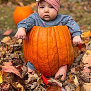 Blair is registered to the contest to win money with this photo: baby, pumpkin, headband, flower, autumn_leaves, fall, outdoor, child, cute, blue_eyes, sitting, seasonal, nature, orange, leaf_litter, portrait, expression, clothing, young_child, garden