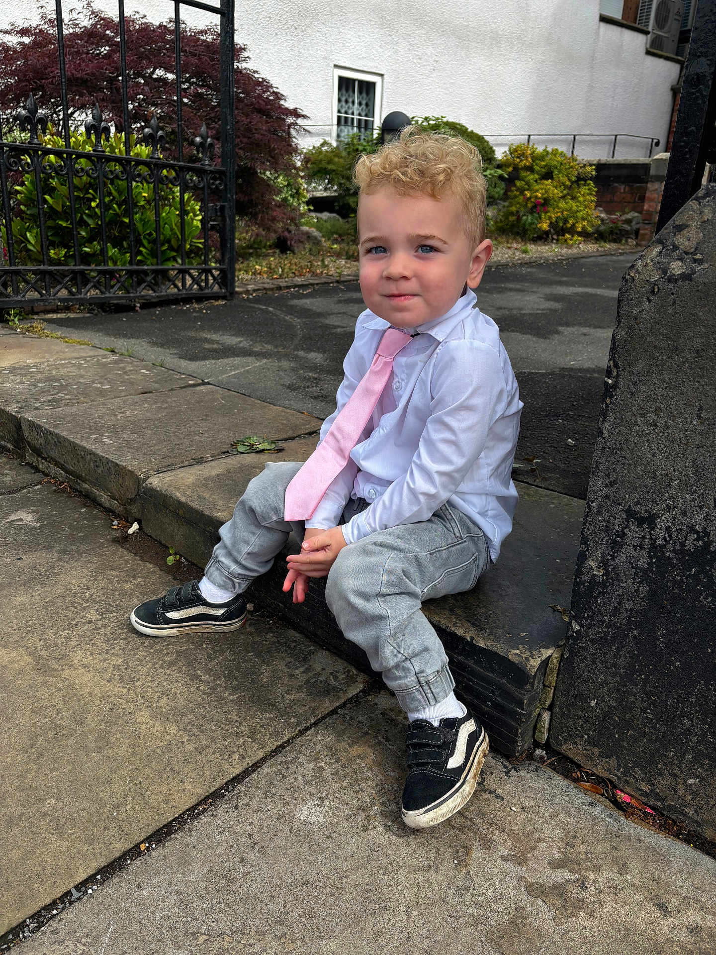 Mason joined the competition — help win amazing prizes! child, boy, curly_hair, white_shirt, pink_tie, grey_pants, black_shoes, outdoor, stone_step, sidewalk, gate, greenery, building, casual, formal, portrait, smile, young, urban, daylight