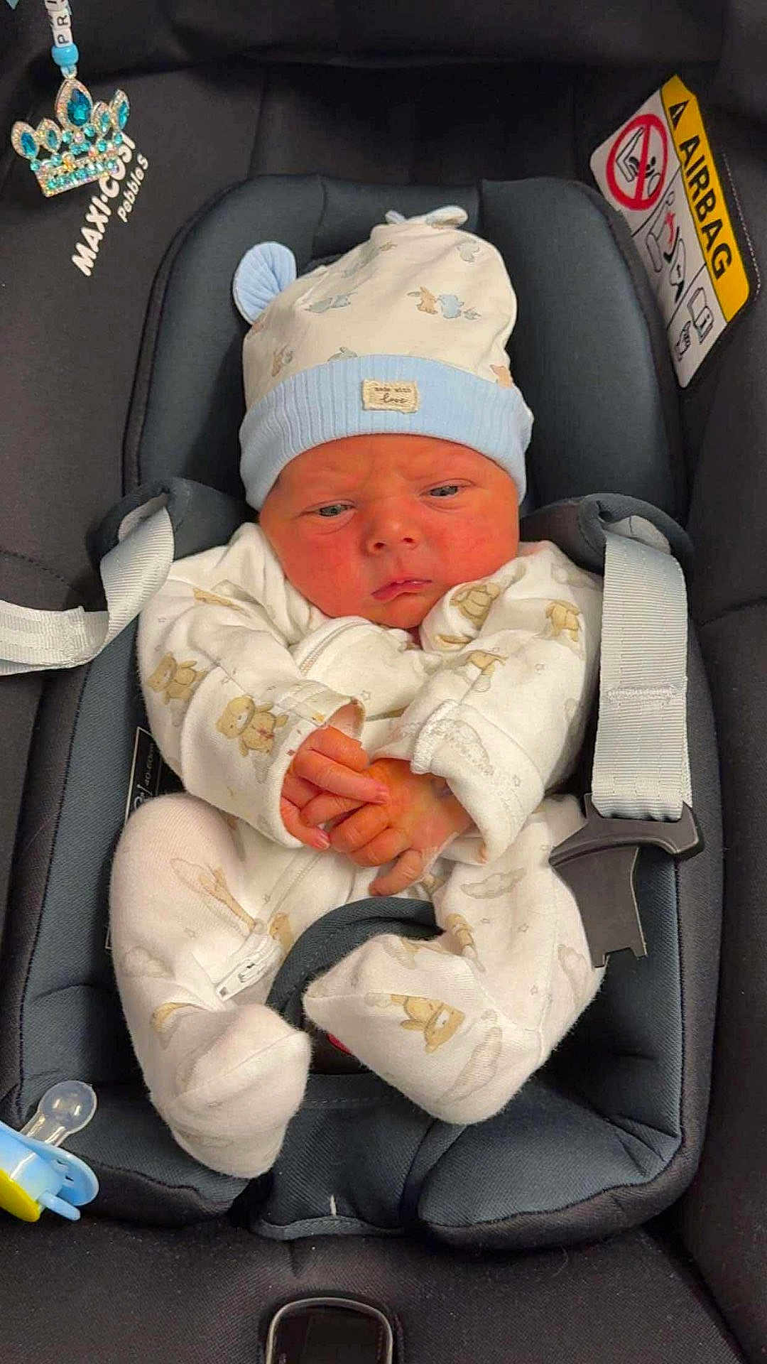 Luca is registered to the contest to win money with this photo: baby, infant, car_seat, hat, onesie, clothing, baby_clothes, cute, child, seat_belt, pacifier, indoor, newborn, portrait, baby_accessory, baby_hat, baby_onesie, sitting, child_seat, serious_expression