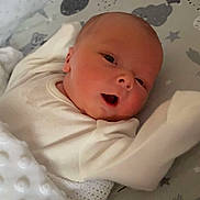 Luca is registered to the contest to win money with this photo: baby, infant, blanket, white_clothing, crib, patterned_sheet, bear_pattern, stars, cute, face, newborn, sleeping_area, soft_texture, infant_bed, child, lying_down, indoors, cozy, comfort, resting