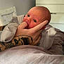 Luca joined the competition — help win amazing prizes! baby, infant, hand, tattoo, finger, person, bed, blanket, furniture, television, room, sleepwear, skin, face, newborn, cute, cozy, indoor, lying_down, curious