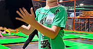 Illia joined the competition — help win amazing prizes! child, boy, smiling, indoor, trampoline_park, playground, foam_block, jumping, recreation, green_mats, orange_rails, sports_facility, short_hair, green_shirt, patterned_shorts, portrait, standing, playful, background_people, safe_play