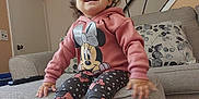 Kilanna joined the competition — help win amazing prizes! toddler, child, smiling, sitting, hoodie, minnie_mouse, leggings, shoes, couch, cushion, living_room, carpet, remote_control, happy, indoor, person, furniture, home, cute, playful