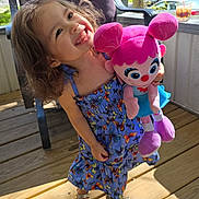 Kilanna joined the competition — help win amazing prizes! child, girl, smiling, plush_toy, dress, butterfly_pattern, sandals, outdoor, wooden_deck, chair, sunlight, happy, toy, curly_hair, summer, daylight, person, cute, playful, nature
