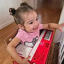Kilanna joined the competition — help win amazing prizes! toddler, child, smiling, box, cardboard, diapers, huggies, indoors, wooden_floor, pink_shirt, hair_buns, happy, playful, person, young_child, floor, wall, home, candid, cute