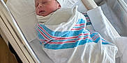 Caleb is registered to the contest to win money with this photo: baby, bassinet, bed, blanket, bottle, card, care, cute, hat, healthcare, hospital, infant, newborn, person, rest, sleeping, striped, swaddled, white, wrapped