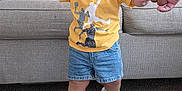 Mkilye joined the competition — help win amazing prizes! toddler, child, smiling, standing, hand_holding, yellow_tshirt, denim_shorts, sneakers, carpet, couch, cushion, living_room, person, happy, indoor, footwear, baby, clothing, hand, portrait