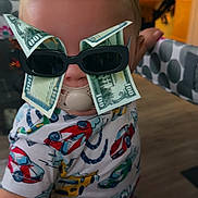 Mkilye joined the competition — help win amazing prizes! arm, baby, car_print, child, clothing, cute, face, furniture, hand, head, highchair, hundred_dollar_bills, indoor, money, pacifier, pattern, person, playful, sunglasses, toddler