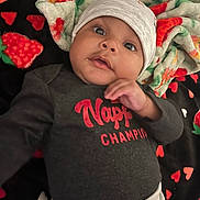 Ourlo is registered to the contest to win money with this photo: baby, blanket, child, clothing, colorful, cute, drool, expression, face, gray_hat, hat, heart_pattern, indoor, infant, looking, lying_down, portrait, red_text, soft_texture, strawberry_pattern
