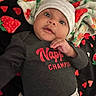baby, blanket, child, clothing, colorful, cute, drool, expression, face, gray_hat, hat, heart_pattern, indoor, infant, looking, lying_down, portrait, red_text, soft_texture, strawberry_pattern