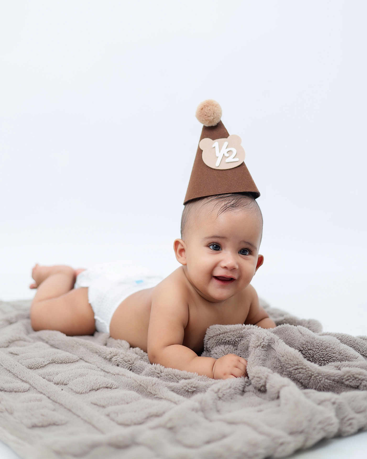 Felipe is registered to the contest to win money with this photo: baby, infant, diaper, blanket, hat, party_hat, smiling, cute, lying_down, soft_texture, celebration, portrait, child, adorable, young, happy, skin, headwear, pom_pom, studio