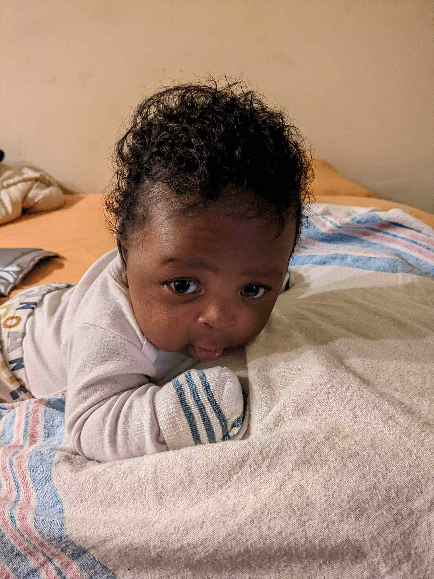 Elijah is registered to the contest to win money with this photo: baby, baby_toddler_clothing, bed_sheet, bedding, bedtime, cheek, child, comfort, flooring, happy, linens, nap, nose, person, room, sitting, sleep, sleeve, smile, t_shirt