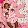 Rivyr is registered to the contest to win money with this photo: baby, baby_shoes, child, comb, dark_skin, diapers, face, flowers, hairbrush, headband, infant, lying_down, makeup_brush, pacifier, perfume, pink, portrait, robe, smiling, three_months
