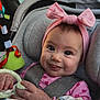 Beatrice is registered to the contest to win money with this photo: accessory, baby, blanket, car_seat, child, closeup, clothing, cute, face, hand, happy, headband, indoor, infant, person, pink, portrait, seatbelt, smile, toy