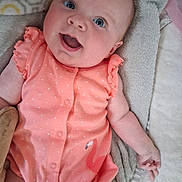 Danielle joined the competition — help win amazing prizes! baby, infant, smiling, blue_eyes, coral_outfit, ruffled_sleeves, blanket, soft_texture, cute, happy, child, portrait, lying_down, indoor, skin, hand, head, face, one_person, clothing