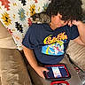 cat, kitten, person, human, curly_hair, sleeping, couch, sofa, blanket, tablet, device, indoors, portrait, pet, animal, relaxed, sitting, shoulder, blue_shirt, home